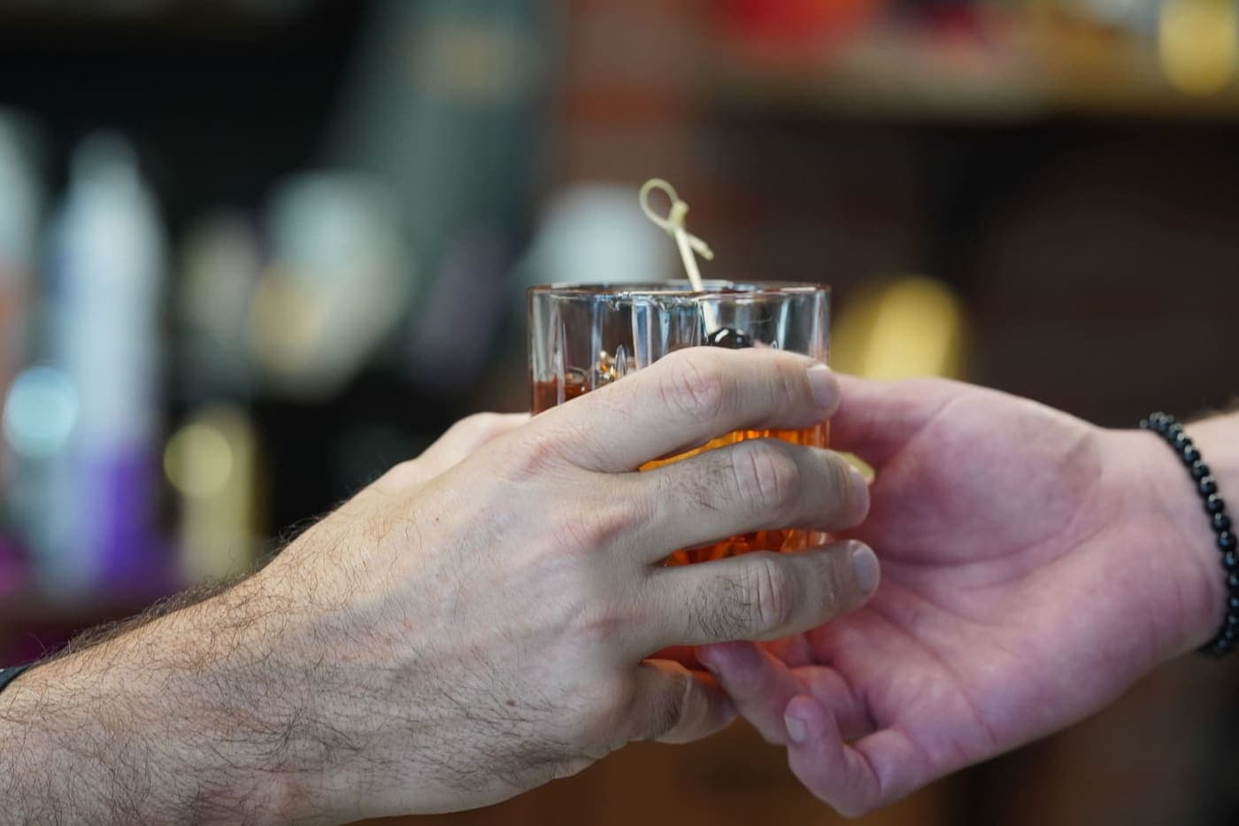 Signature Old Fashioned being handed to a client