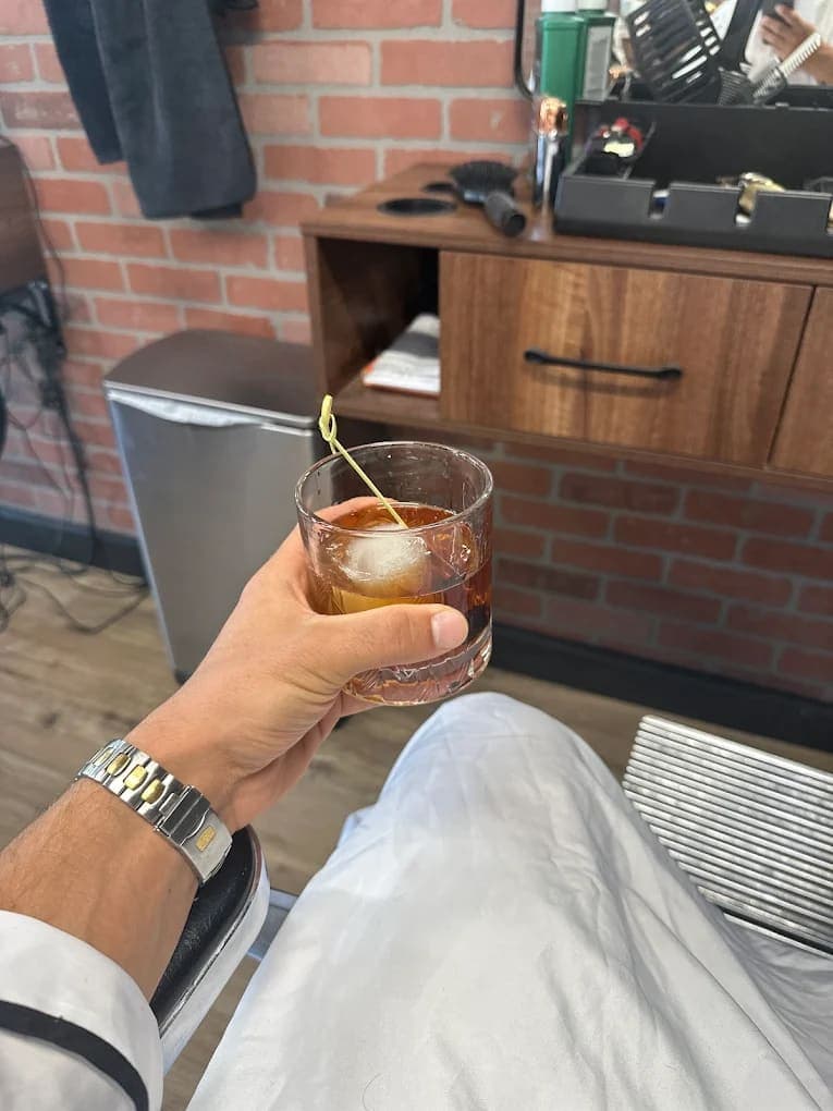 Client enjoying an Old Fashioned cocktail in the barber chair