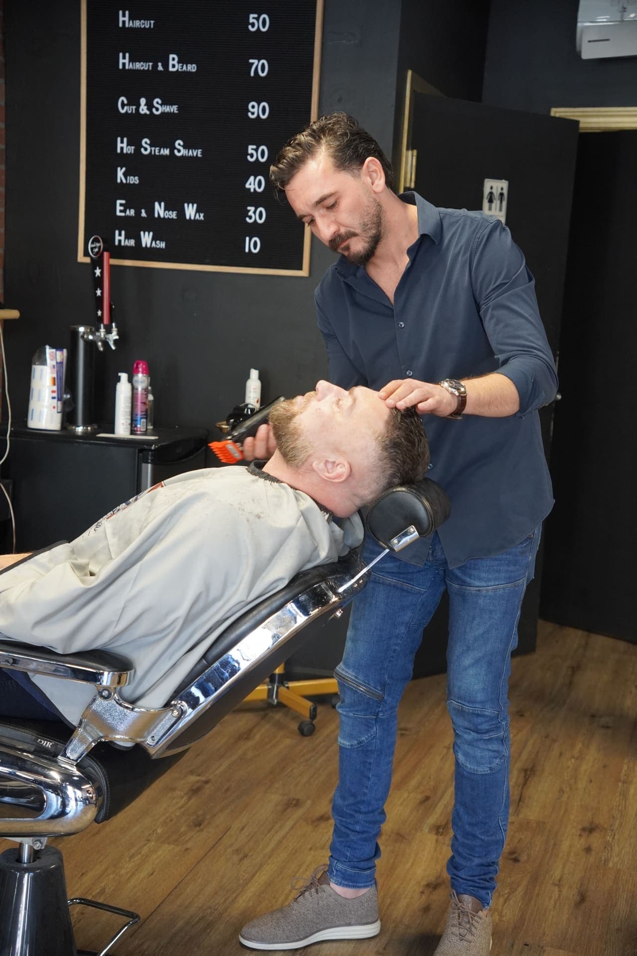 Barber working at the station with brick wall backdrop