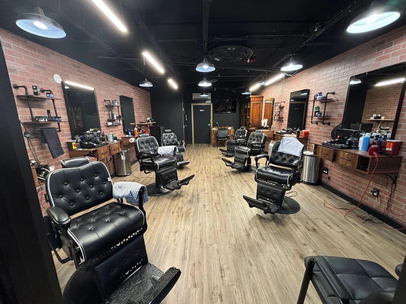 Full shop interior with leather barber chairs and brick walls